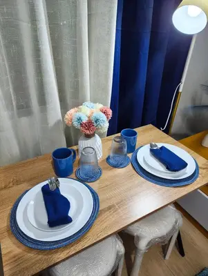 a wooden table with blue and white plates and flowers at Studio City Staycation in Manila