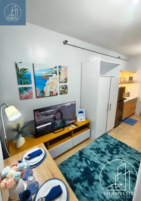 a living room with a table and a tv at Studio City Staycation in Manila
