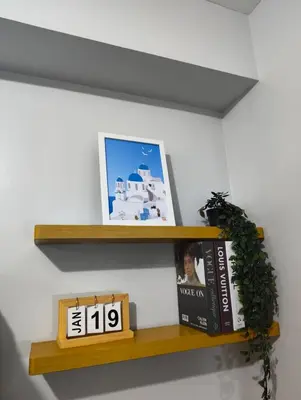 a shelf with books and a picture and a clock at Studio City Staycation in Manila