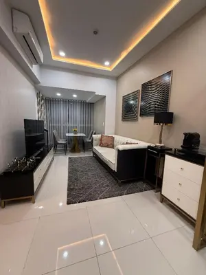 a large living room with a couch and a tv at Cozy Apartment with Private Room in Vibrant Taguig in Manila