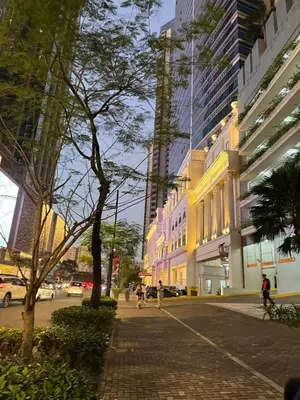 a city street with buildings and people walking on the sidewalk at Cozy Apartment with Private Room in Vibrant Taguig in Manila