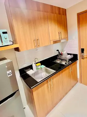 a kitchen with a sink and wooden cabinets at Shore 3, Mall of Asia Complex in Manila