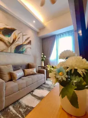a living room with a couch and a vase of flowers at Shore 3, Mall of Asia Complex in Manila