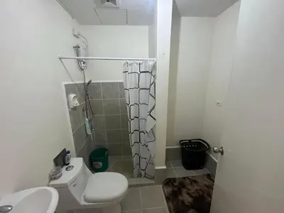 a bathroom with a white toilet and a shower at Nuvali Amaia steps parkway in Calamba