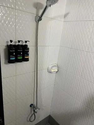 a shower with three bottles on a wall at Cozy Loft Unit in Manila in Manila