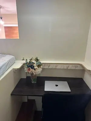 a small table with a laptop and flowers on it at Cozy Loft Unit in Manila in Manila