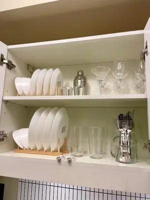 a cupboard filled with plates and dishes and glasses at Balé Cù Calathea Place near airport road NAIA and MOA in Manila