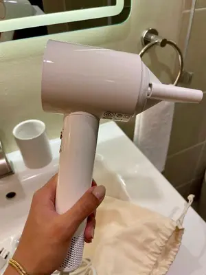 a person holding a blow dryer in front of a sink at Balé Cù Calathea Place near airport road NAIA and MOA in Manila