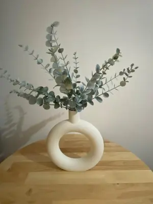 a white vase with flowers in it on a table at Kasara T14K Cozy Abode in Manila