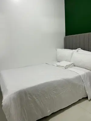 a white bed with white sheets and pillows on it at MK's place in Manila
