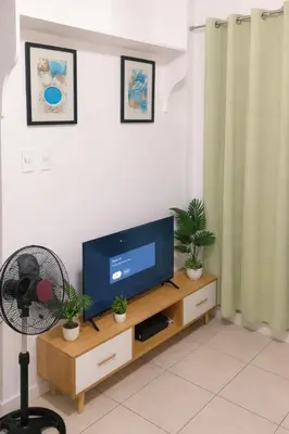 a living room with a television on a wooden entertainment center at Condotels in Sucat Road in Manila