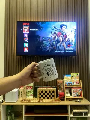 a person holding a cup in front of a tv at The Azelea Suites By Azel in Manila