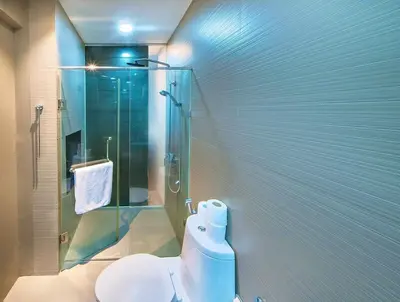 a bathroom with a toilet and a glass shower at Haven in the Park in Manila