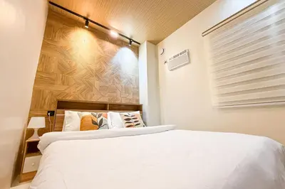 a bedroom with a white bed and a wooden wall at Lunan by SKI - Boutique Hotel in Taytay Rizal in Taytay