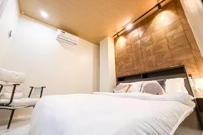 a bedroom with two beds and a chair at Lunan by SKI - Boutique Hotel in Taytay Rizal in Taytay