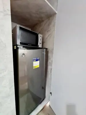 a microwave sitting on top of a refrigerator at Cozy MOA View Stay - Walk to Mall of Asia in Manila
