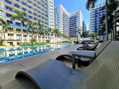 a park with benches and a pool with buildings at Cozy MOA View Stay - Walk to Mall of Asia in Manila