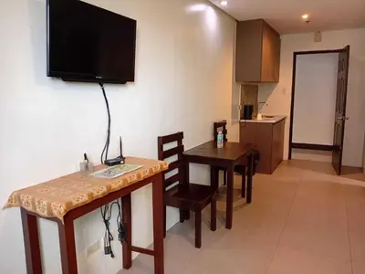 a living room with a table and a television on the wall at Shandong Residences in Manila