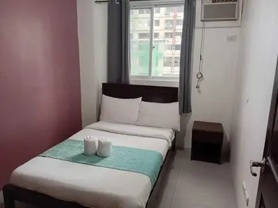 a bedroom with a bed with two white towels on it at Shandong Residences in Manila