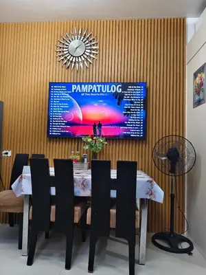a dining room with a table and a tv on the wall at Juliza Staycation near Mall Of Asia in Manila
