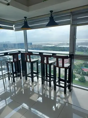 a bar with chairs and tables in a room with windows at Your Home Near the Airport in Manila