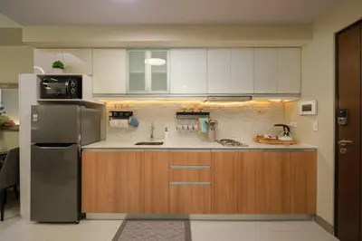 a kitchen with a stainless steel refrigerator and wooden cabinets at Modern & Stylish Condo at One Uptown Residence in Manila