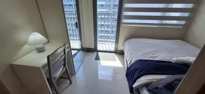 a bedroom with a bed and a desk and two windows at JCs Staycation Fame Residences in Manila
