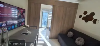 a living room with a black couch and a tv at JCs Staycation Fame Residences in Manila