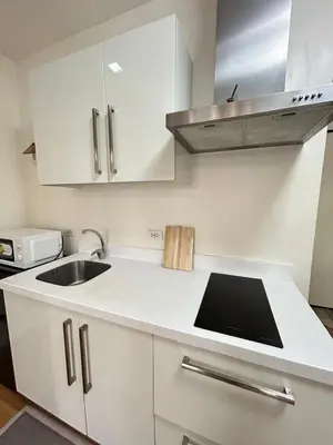 a kitchen with white cabinets and a sink at Roomi Stays Acqua Private Residences in Manila