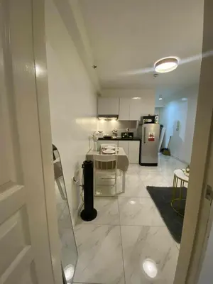 a white kitchen with a table and a refrigerator at D'Hauz 2- Pet Friendly unit in Manila