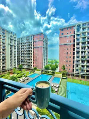 a person holding a cup of coffee on a balcony at D'Hauz 2- Pet Friendly unit in Manila