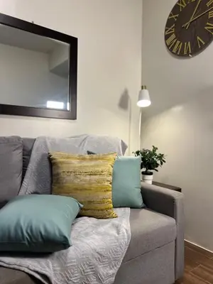 a living room with a couch with pillows and a clock at Prime Makati CBD Condo with Fast WiFi in Manila