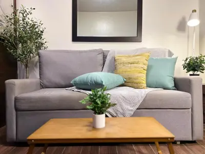a living room with a gray couch with pillows at Prime Makati CBD Condo with Fast WiFi in Manila