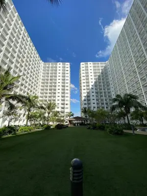 two large white buildings with palm trees in a park at Cozy 1 BR unit at Shore 1 Residences Mall of Asia in Manila