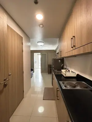 a kitchen with wooden cabinets and a black counter top at Cozy 1 BR unit at Shore 1 Residences Mall of Asia in Manila