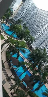 a large building with palm trees in front of it at Staycation by Jia cozy corner in Manila
