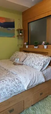 a bedroom with a large bed with a wooden headboard at Staycation by Jia cozy corner in Manila