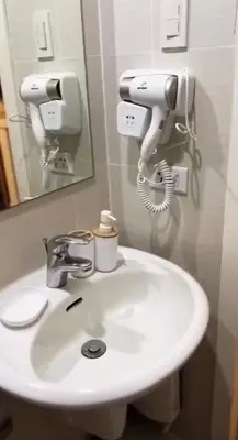 a bathroom sink with a hair dryer and a mirror at Azure SYM Staycation in Manila