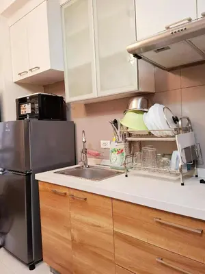 a kitchen with a sink and a refrigerator at Sunshine100 1Bedroom 65InchesTV PoolGymBilliardPlayground in Manila