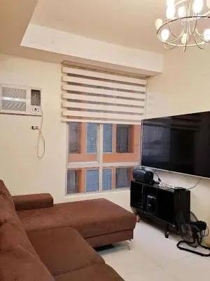 a living room with a couch and a flat screen tv at Sunshine100 1Bedroom 65InchesTV PoolGymBilliardPlayground in Manila