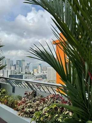 a view of a city from a balcony with plants at Sunshine100 1Bedroom 65InchesTV PoolGymBilliardPlayground in Manila