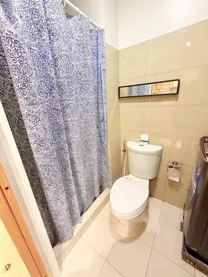 a bathroom with a toilet and a blue shower curtain at Bayshore Getaway Condotel by Clowie in Manila
