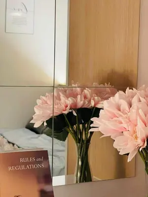 a vase of pink flowers in front of a mirror at Bayshore Getaway Condotel by Clowie in Manila