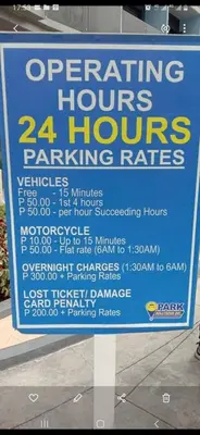 a sign for parking hours and parking rates on a street at Casa Laelia in Manila