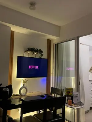 a living room with a table and a tv on the wall at CozyCorner By R&K in Manila
