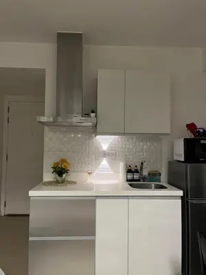 a white kitchen with white cabinets and a sink at CozyCorner By R&K in Manila