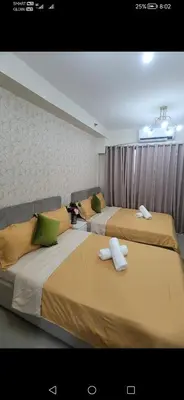 two beds in a room with yellow and green pillows at Classy Stay in Manila