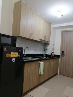 a kitchen with a black refrigerator and wooden cabinets at Classy Stay in Manila