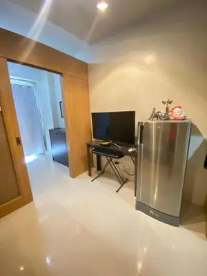 a living room with a refrigerator and a desk at Budget Condo in Mall Of Asia in Manila