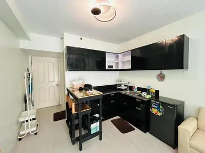 a kitchen with black cabinets and a black refrigerator at Ports Den in Manila